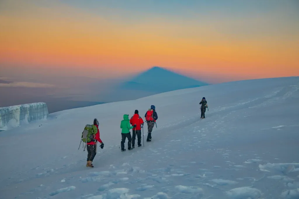 Climbers crossing snowy Kilimanjaro terrain at dawn