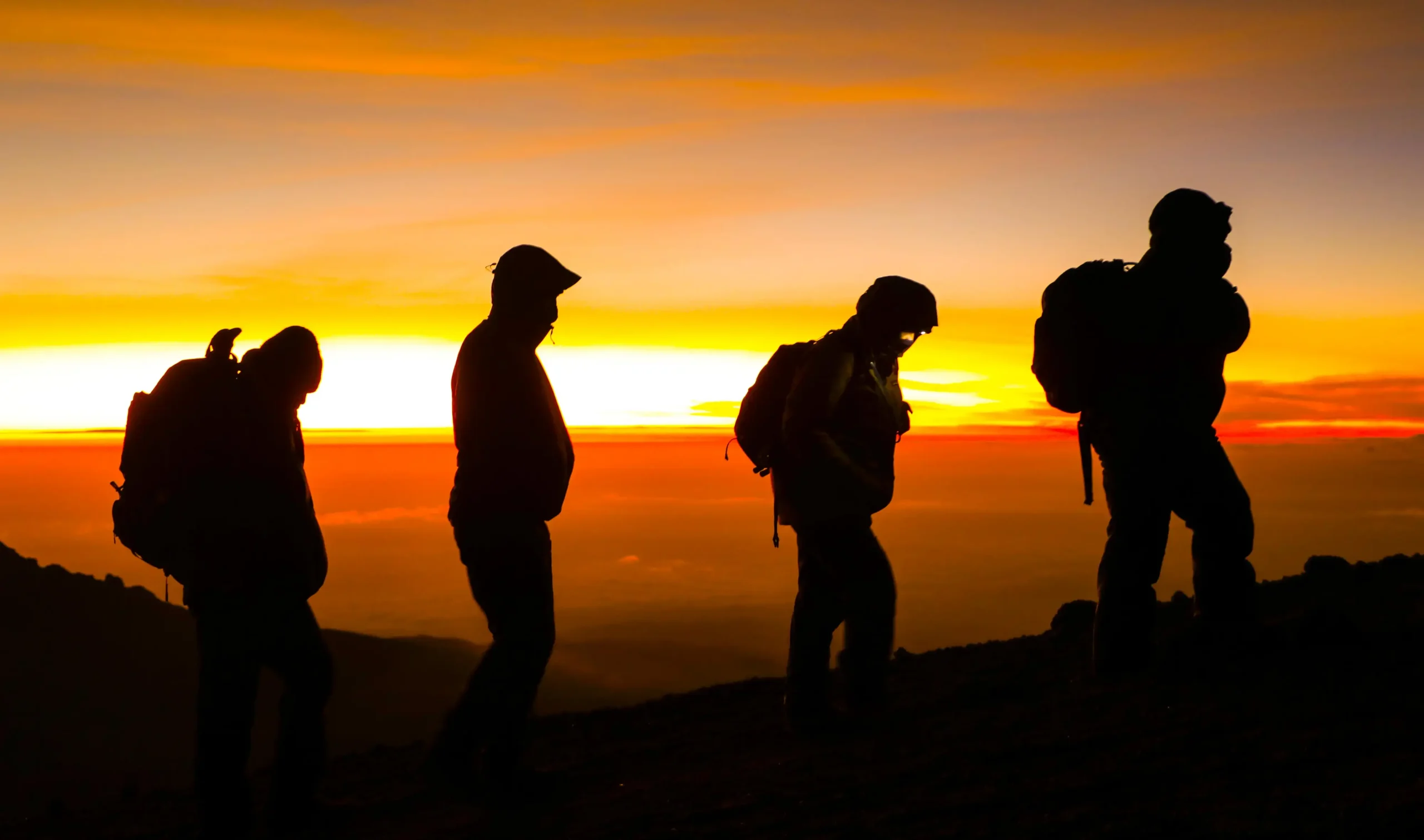 Climbers ascending Kilimanjaro's Barafu Camp with Uhuru Peak in the background — altitude sickness is the primary reason summit attempts fail
